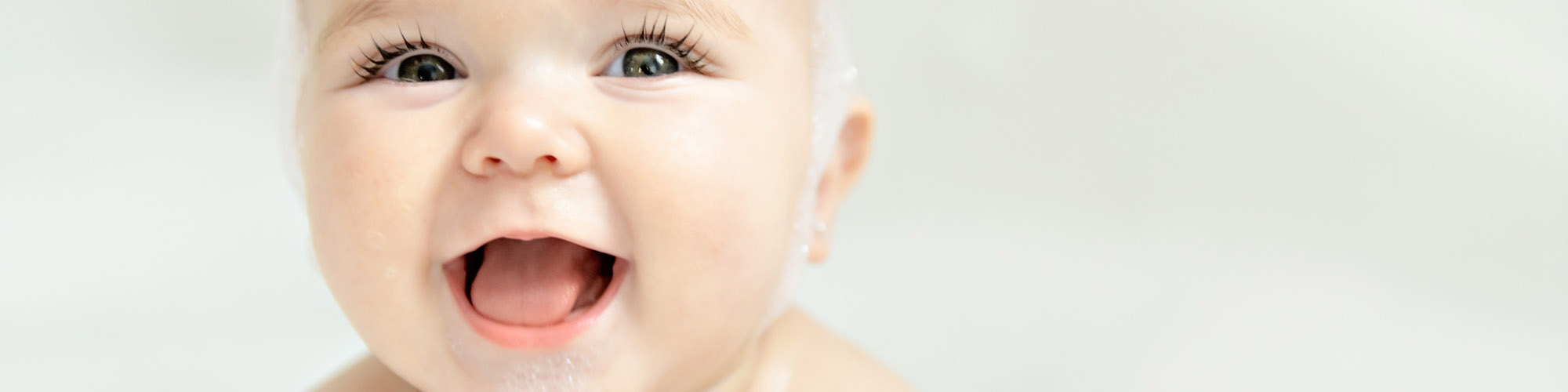 A Baby girl bathes in a bath with foam and soap bubbles