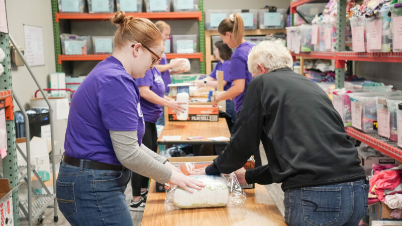 Group of People Volunteering in the warehouse wrapping diapers