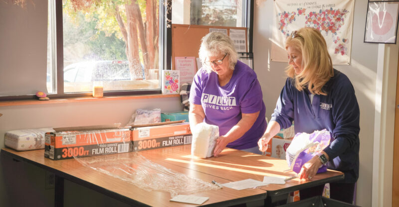 2 Volunteers wrapping diapers in purple shirts