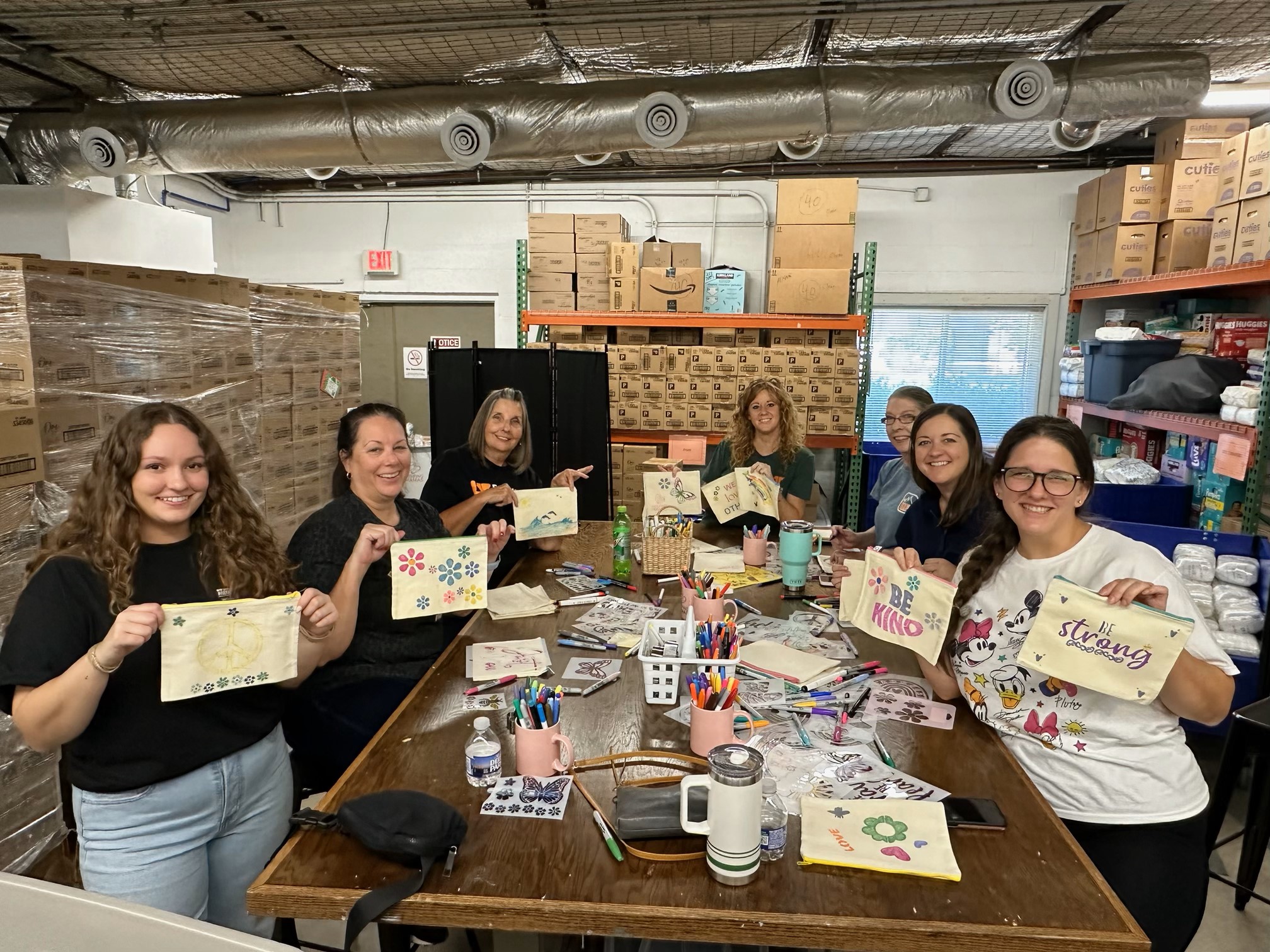 3 Women Decorating Period Packs in a Purple Shirt 