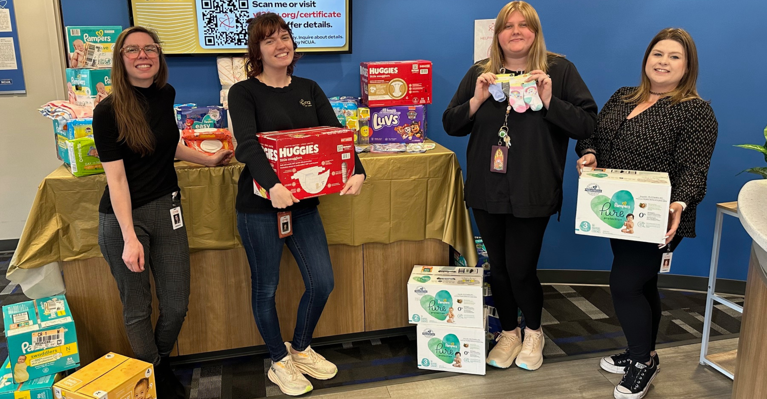 The Travlers Insurance Team posing in front of the van with their diaper donations and check 